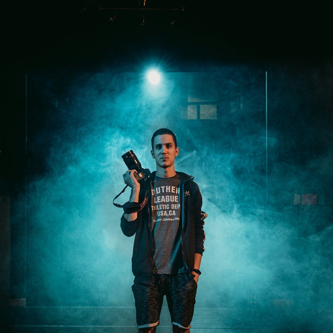 Male media instructor holding a professional video camera in a studio